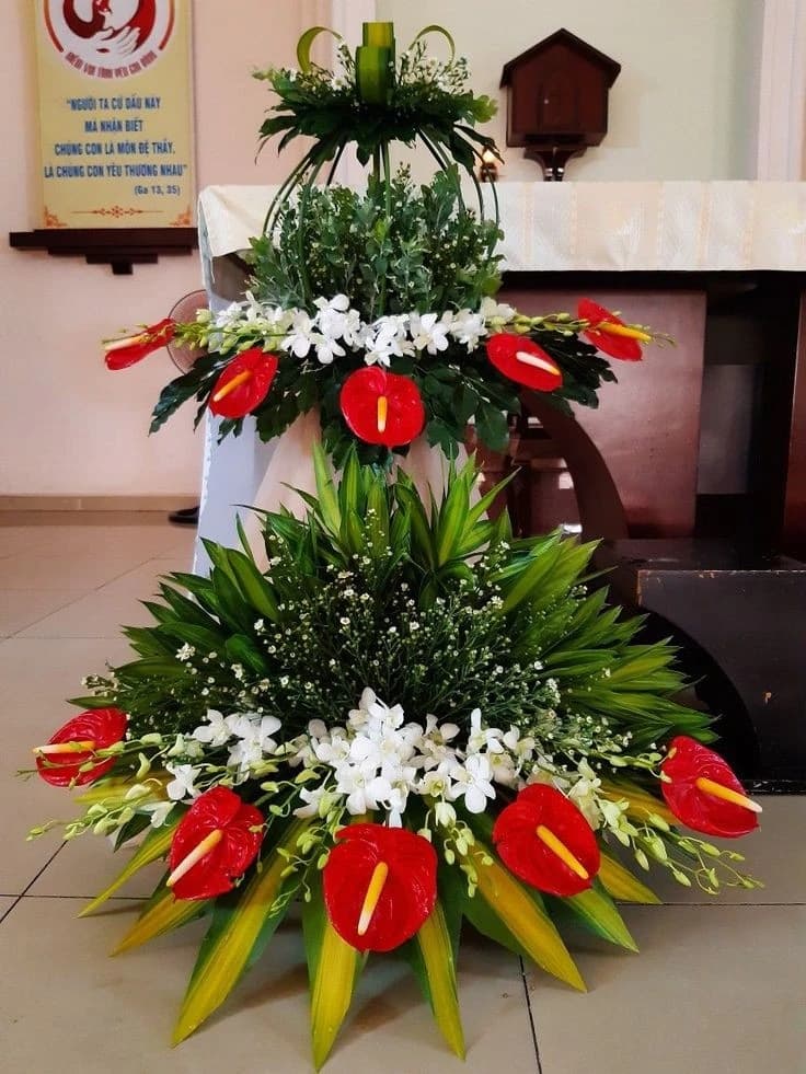 Composition florale exotique à deux niveaux avec des anthuriums rouges, des orchidées blanches et une verdure tropicale luxuriante