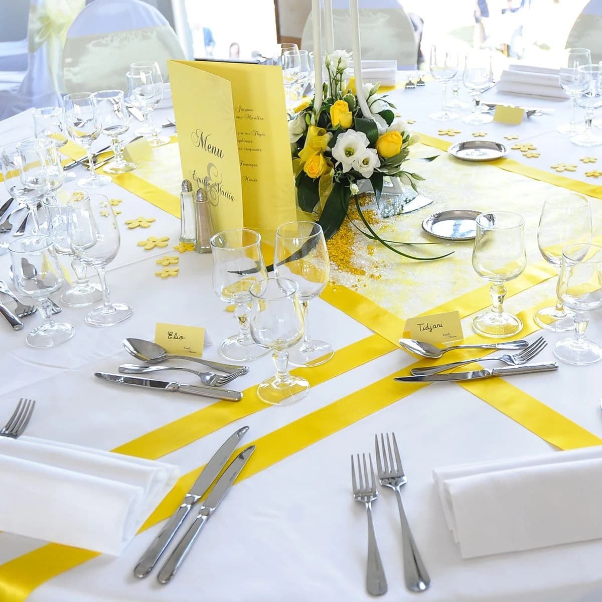 Mise en table lumineuse sur le thème des agrumes avec des rubans jaunes, un menu jaune et un centre de table assorti